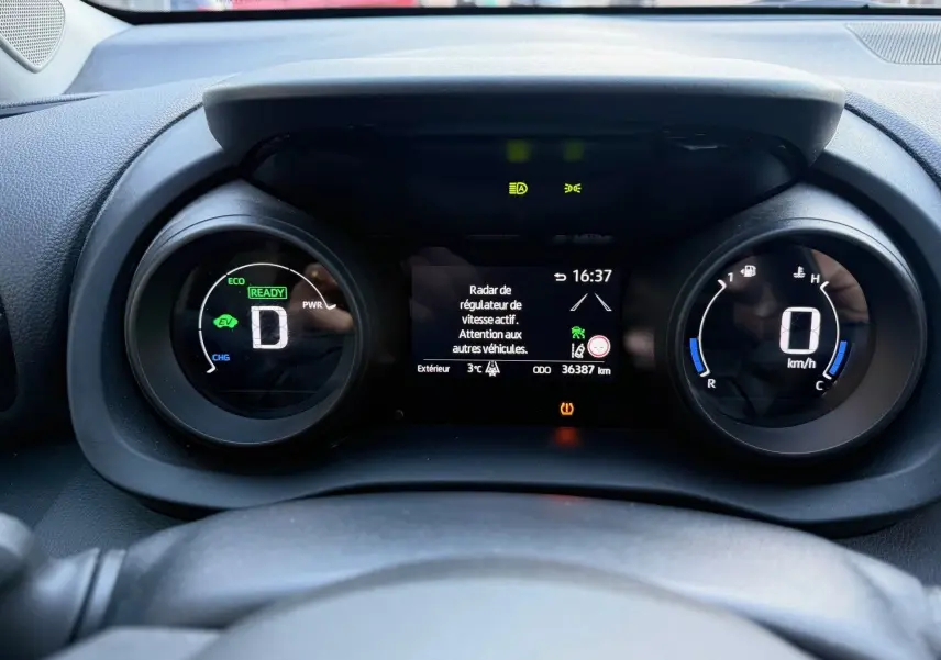 Tableau de bord de Toyota Yaris Hybride bleu métal 2021, affichage numérique du compteur et régulateur actif à 16h37.