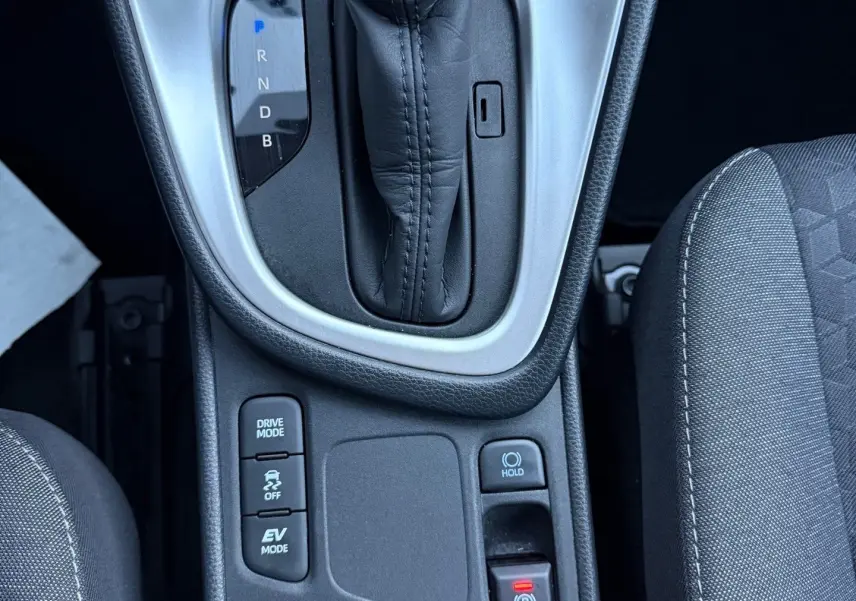 Vue plongeante sur la console centrale de la Toyota Yaris Hybride 2021, avec levier de vitesse automatique et boutons de modes de conduite.