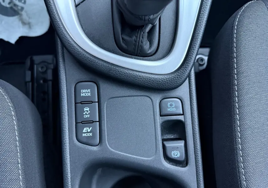 Gros plan sur la console centrale de la Toyota Yaris Hybride 2021, montrant les boutons Drive Mode et frein électronique.