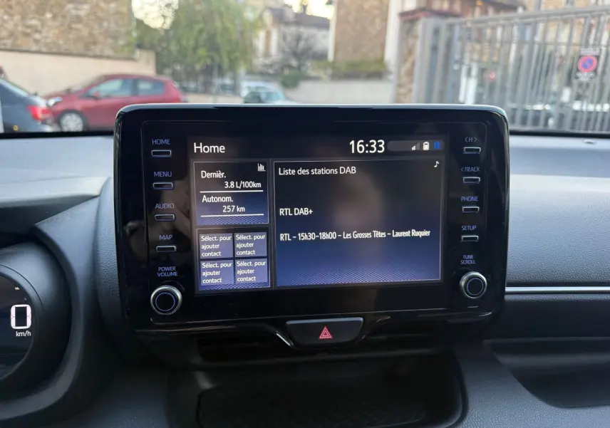 Écran tactile central de la Toyota Yaris Hybride 2021 affichant la liste des stations DAB et la consommation instantanée