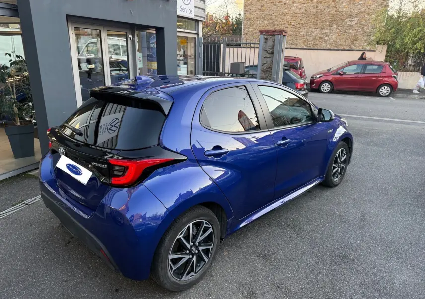 Vue 3/4 arrière droite d'une Toyota Yaris Hybride Design 116h bleu métal avec toit noir et jantes alliage distinctives.