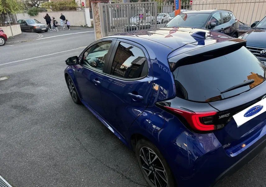 Vue 3/4 arrière droite d'une Toyota Yaris Hybride Design 116h bleu métal avec toit noir et feux LED distinctifs.