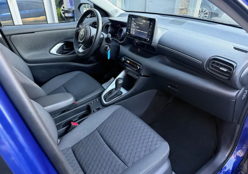 Intérieur côté conducteur de la Toyota Yaris Hybride bleu métal 2021, avec tableau de bord moderne et écran tactile central.