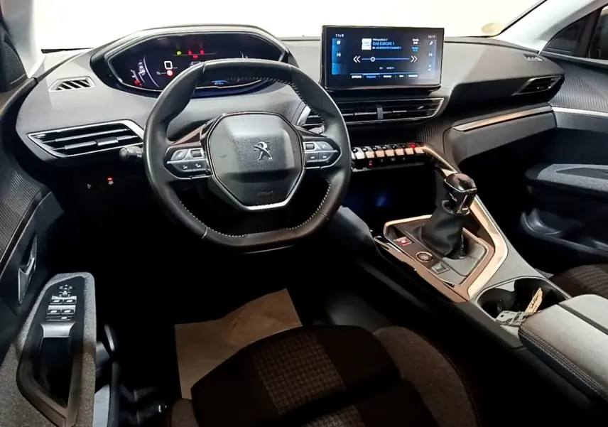 Vue intérieure du poste de conduite du Peugeot 3008 noir, avec volant cuir, écran tactile central et levier de vitesse manuel.