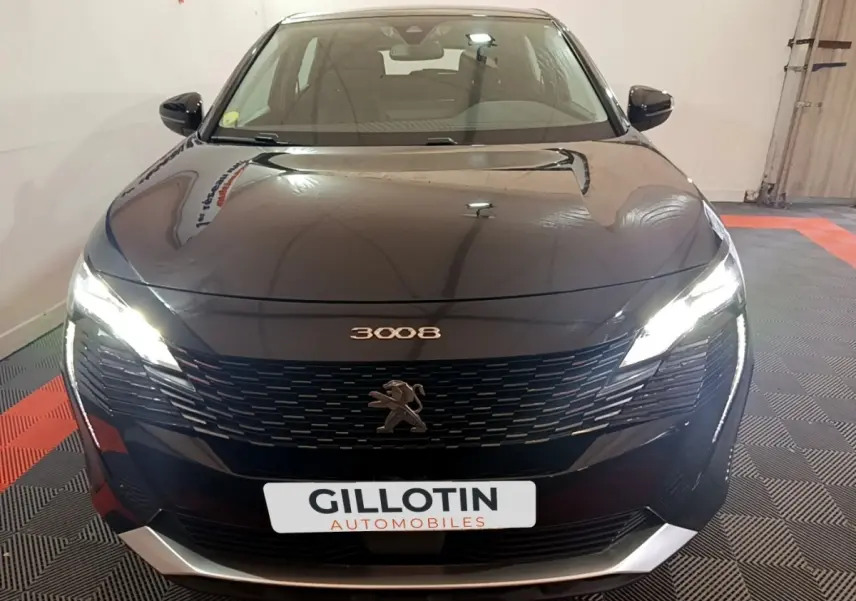Vue avant du Peugeot 3008 noir 2022 avec phares allumés et calandre distinctive en intérieur showroom.
