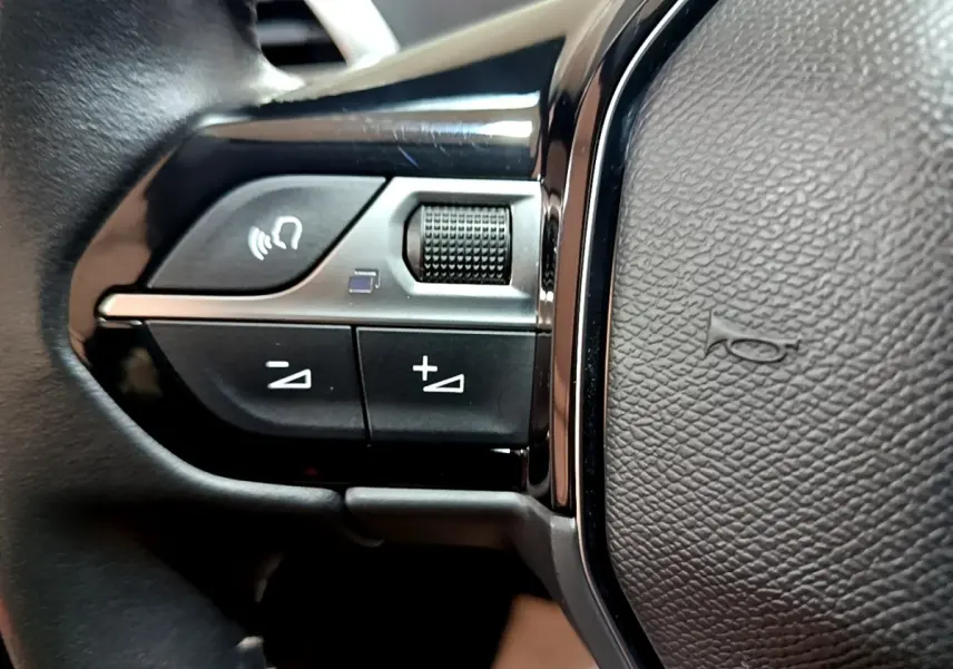 Gros plan sur les commandes gauche du volant noir du Peugeot 3008 2022, avec boutons de volume et commande vocale.