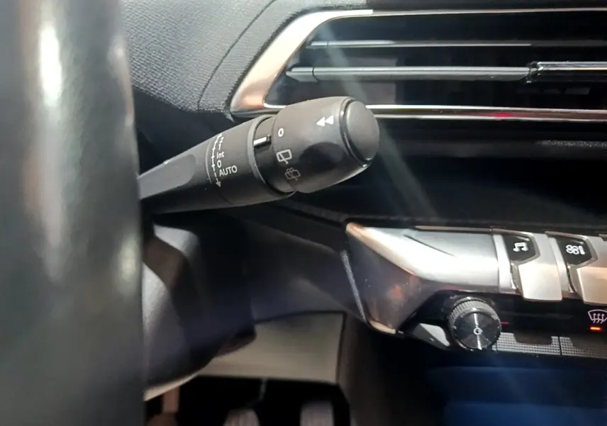 Gros plan sur la commande d’essuie-glace à gauche du volant dans l’habitacle noir du Peugeot 3008 2022.
