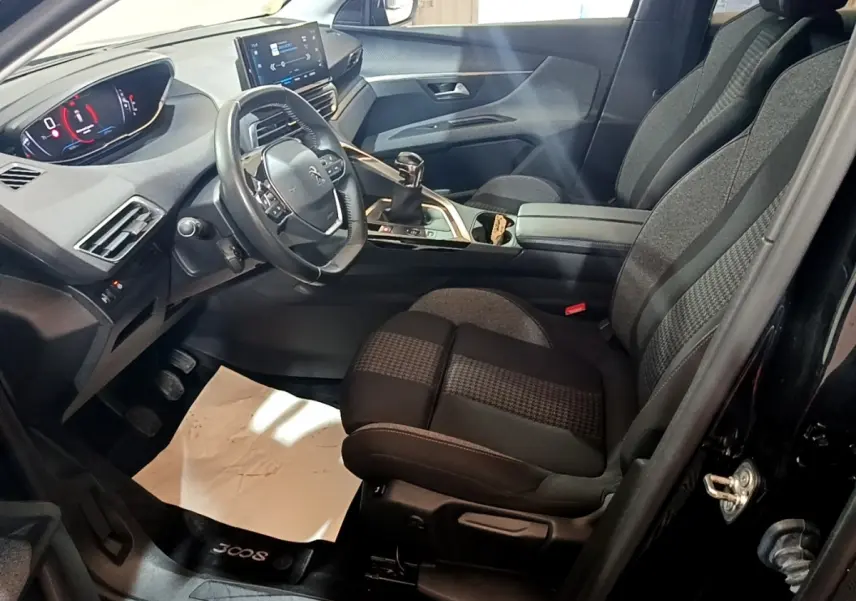 Vue intérieure côté conducteur du Peugeot 3008 noir 2022, avec tableau de bord numérique et sièges tissu bicolores.
