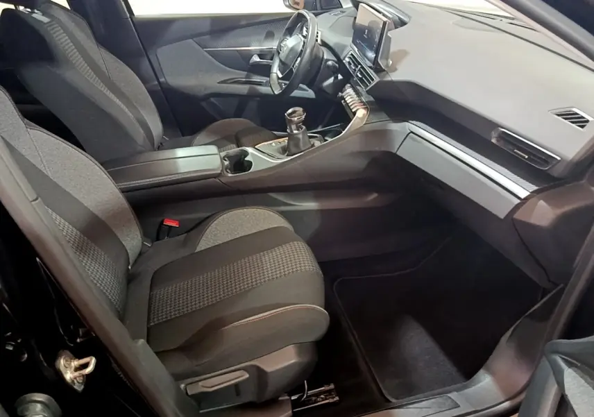 Vue intérieure côté passager du Peugeot 3008 noir 2022, avec tableau de bord moderne et boîte manuelle.