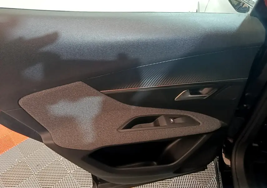 Vue intérieure du panneau de porte côté gauche du Peugeot 3008 noir, avec insert texturé et poignée métallique.