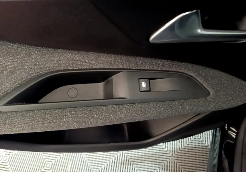 Détail de la commande de lève-vitre côté gauche intérieur d’une Peugeot 3008 noir, tissu gris.