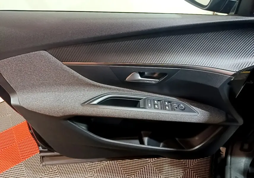 Vue intérieure côté gauche de la porte avant noire du Peugeot 3008 2022 avec commandes de vitres et poignée chrome.
