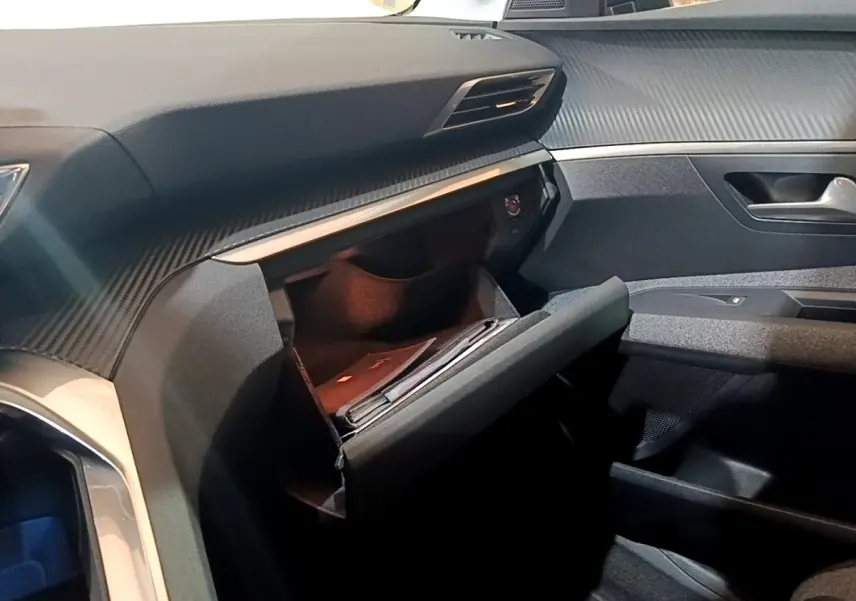 Vue intérieure côté passager du tableau de bord noir du Peugeot 3008 2022 avec boîte à gants ouverte et détails de la garniture.