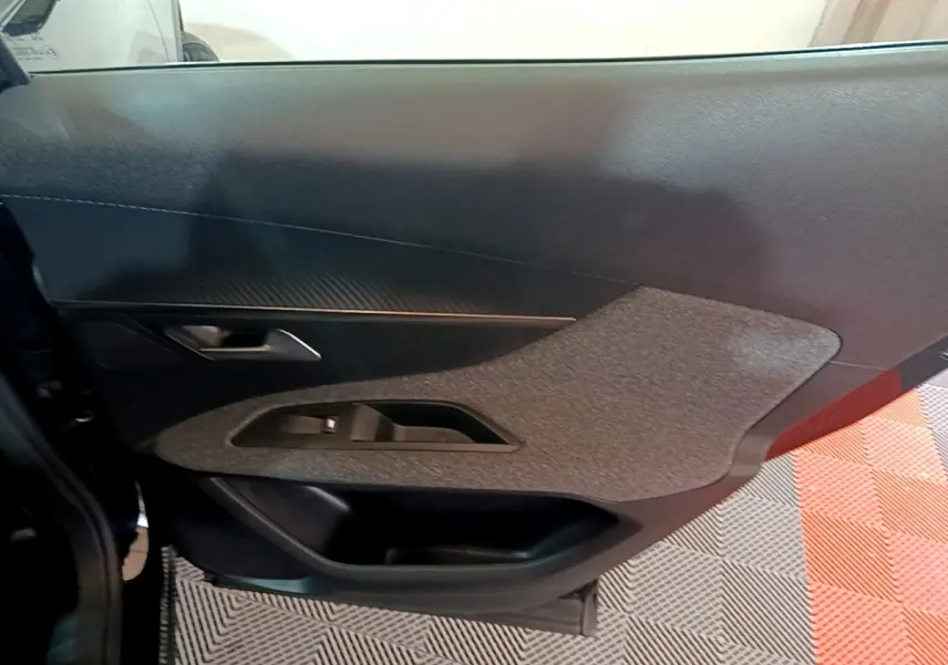 Vue intérieure du panneau de porte côté gauche d'une Peugeot 3008 noir, avec insert tissu gris et commande de lève-vitre.