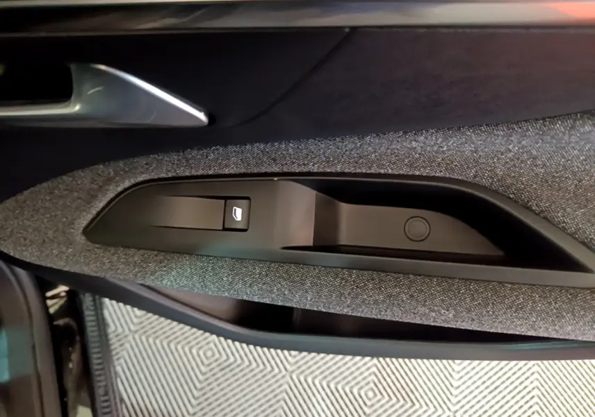 Gros plan sur la commande de lève-vitre côté conducteur de la porte intérieure d’une Peugeot 3008 noire, finition tissu gris.