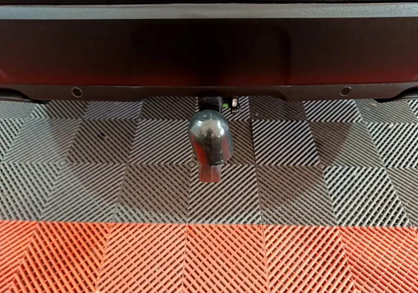 Gros plan sur l'attelage noir du Peugeot 3008 BlueHDi 130 S&S Active Pack, vu de l'arrière sur un sol à damiers gris et rouge.