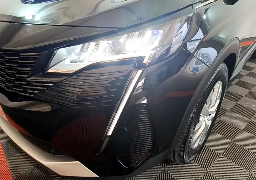 Gros plan sur l'avant droit noir brillant du Peugeot 3008 avec phare LED allumé et jante visible.