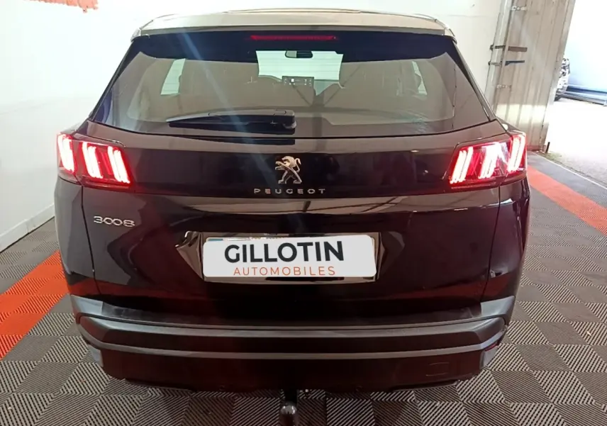 Vue arrière d'un Peugeot 3008 noir 2022 avec feux arrière allumés et attelage visible en intérieur showroom.