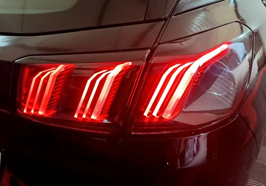 Gros plan sur le feu arrière droit rouge allumé d’un Peugeot 3008 noir, version BlueHDi 130 S&S Active Pack 2022.