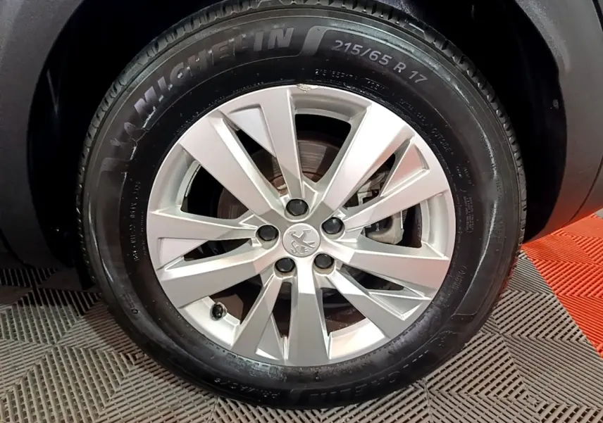 Gros plan sur la roue avant droite d’un Peugeot 3008 noir, jante alliage argentée et pneu Michelin 215/65 R17.