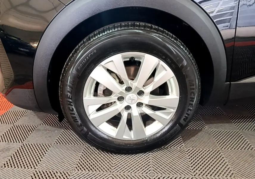 Gros plan sur la roue avant droite du Peugeot 3008 noir, mettant en valeur la jante alliage et le pneu Michelin.