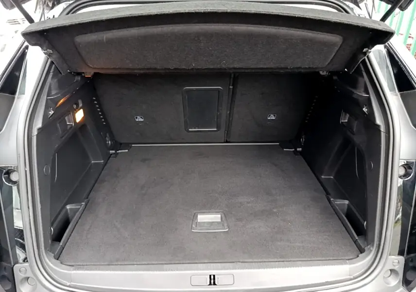 Coffre ouvert vu de l'arrière d'un Peugeot 3008 noir, montrant un espace de chargement propre et spacieux.