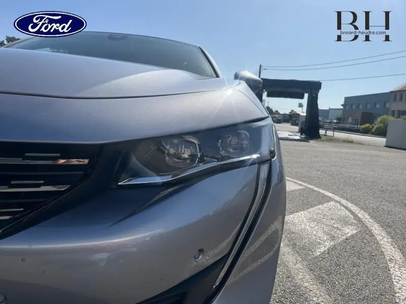 Gros plan sur l'avant droit gris Artense d'une Peugeot 508 SW 2021, mettant en valeur le phare et la calandre.