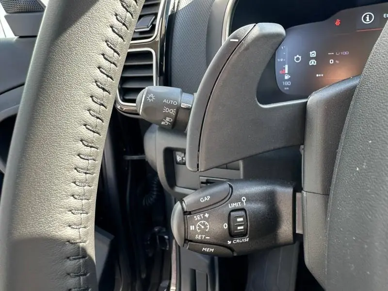 Détail du volant côté gauche du Citroën C5 Aircross 2025 gris Platinium, montrant les commandes de régulateur et feux.