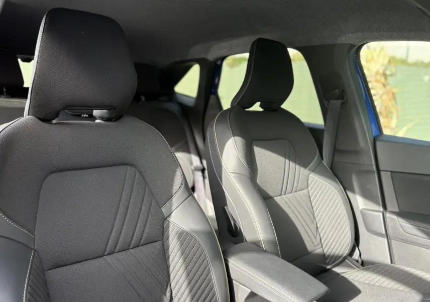 Vue intérieure des sièges avant en tissu noir avec surpiqûres claires de la Renault Symbioz E-Tech Full Hybrid 2025.