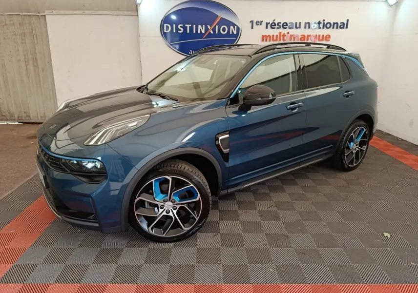 Vue 3/4 avant droite d'un SUV LINK & CO 01 hybride rechargeable bleu avec jantes sport bicolores en intérieur showroom.