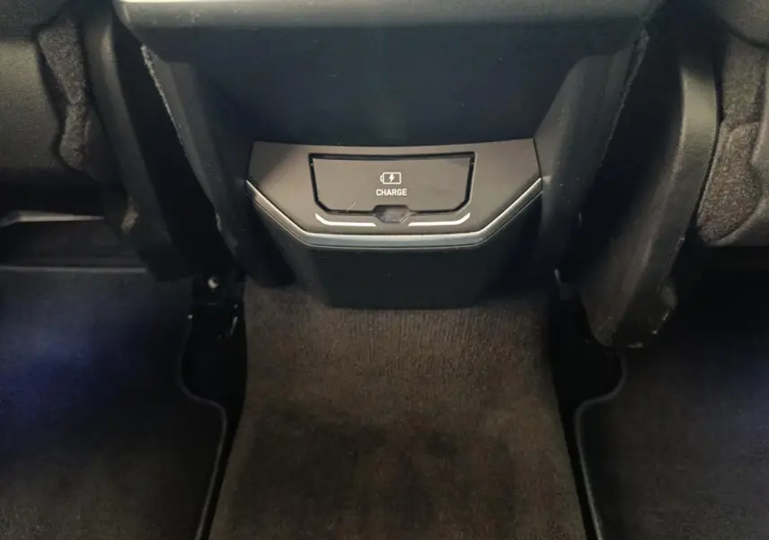 Gros plan sur la console centrale arrière noire avec zone de recharge sans fil du Link & Co 01 hybride rechargeable.