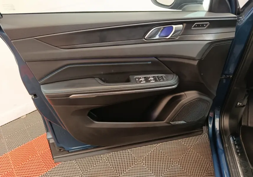 Vue intérieure côté gauche de la porte avant bleu du Link & Co 01 avec commandes électriques et haut-parleur intégré.