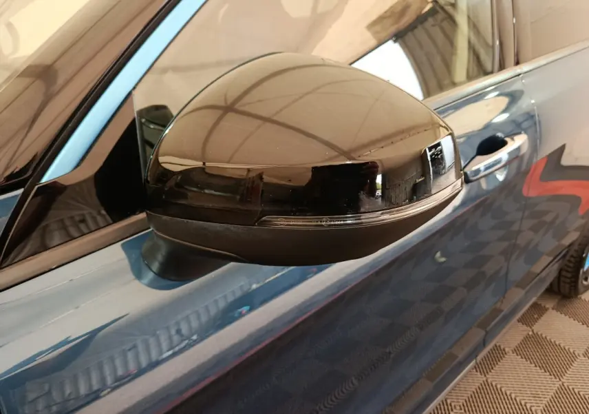 Gros plan sur le rétroviseur droit noir brillant du SUV bleu Link & Co 01 hybride rechargeable, avec poignée de porte visible.