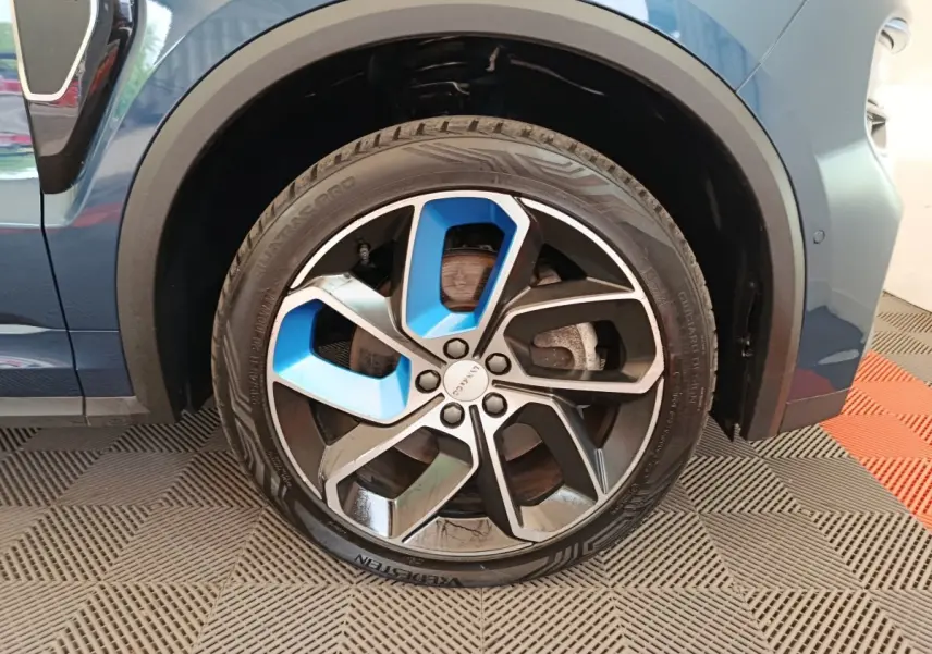 Gros plan sur la roue avant droite bleu et noir du SUV Link & Co 01 hybride rechargeable 2022, avec jante stylisée.