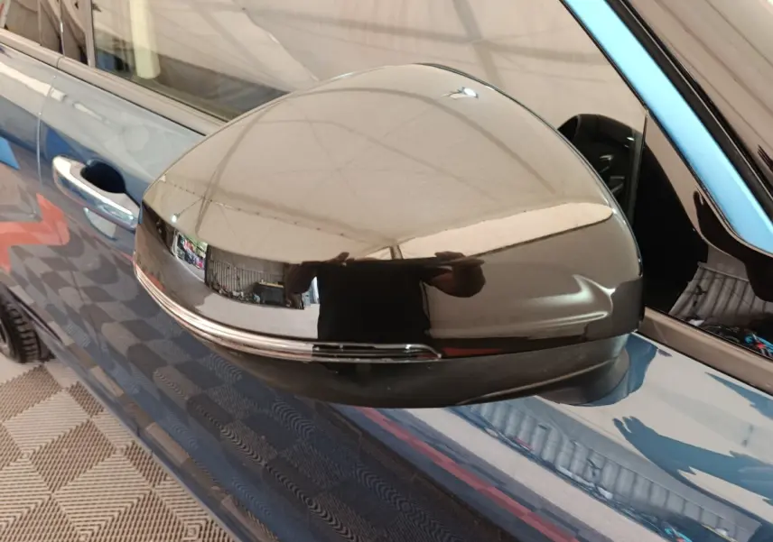 Gros plan sur le rétroviseur droit noir brillant du SUV bleu Link & Co 01 hybride rechargeable, reflet intérieur visible.