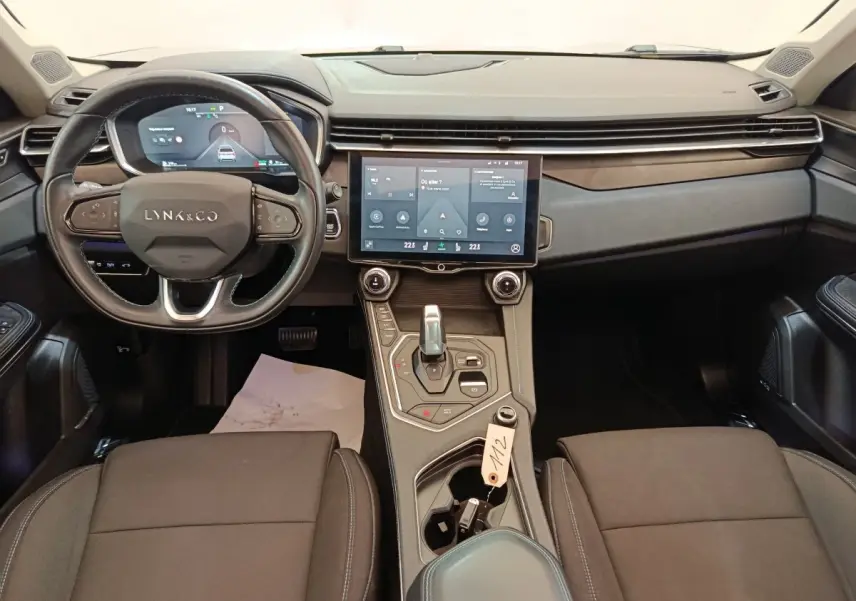 Vue intérieure avant du tableau de bord et volant noir du Lynk & Co 01 hybride rechargeable avec écran tactile central.