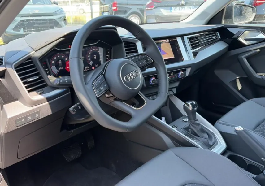 Vue intérieure côté conducteur de l'Audi A1 Sportback 30 TFSI 2026 avec volant cuir multifonction et console centrale moderne.