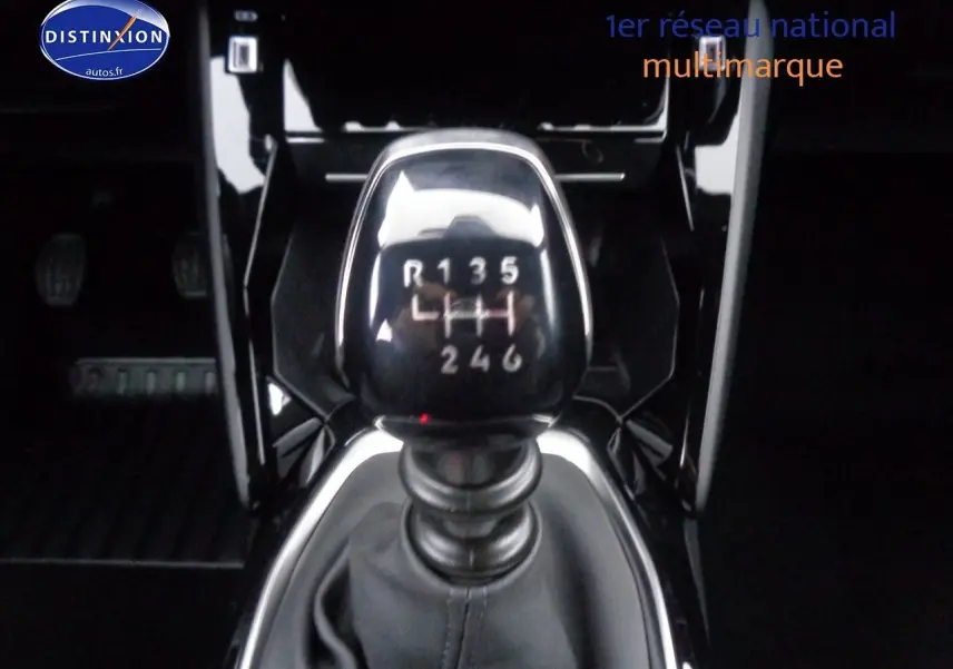 Le levier de vitesses manuel en gros plan dans l'habitacle noir brillant d'une Peugeot 2008 rouge Elixir Metal 2023.