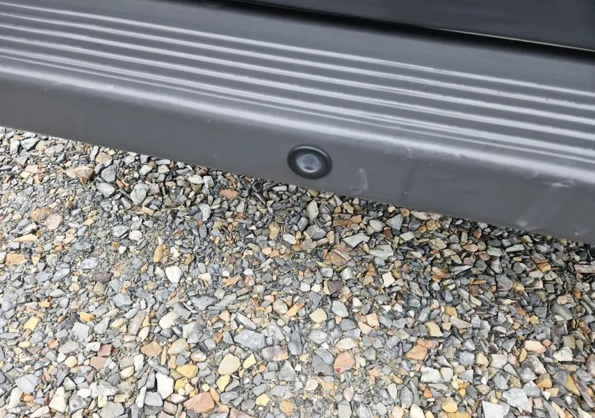 Gros plan sur le bas de caisse noir avec capteur de stationnement du Fiat Ducato Combi blanc, vue latérale basse.