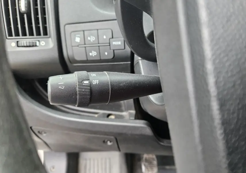 Gros plan sur la commande d'essuie-glace noire à gauche du volant dans l'habitacle du Fiat Ducato Combi blanc.