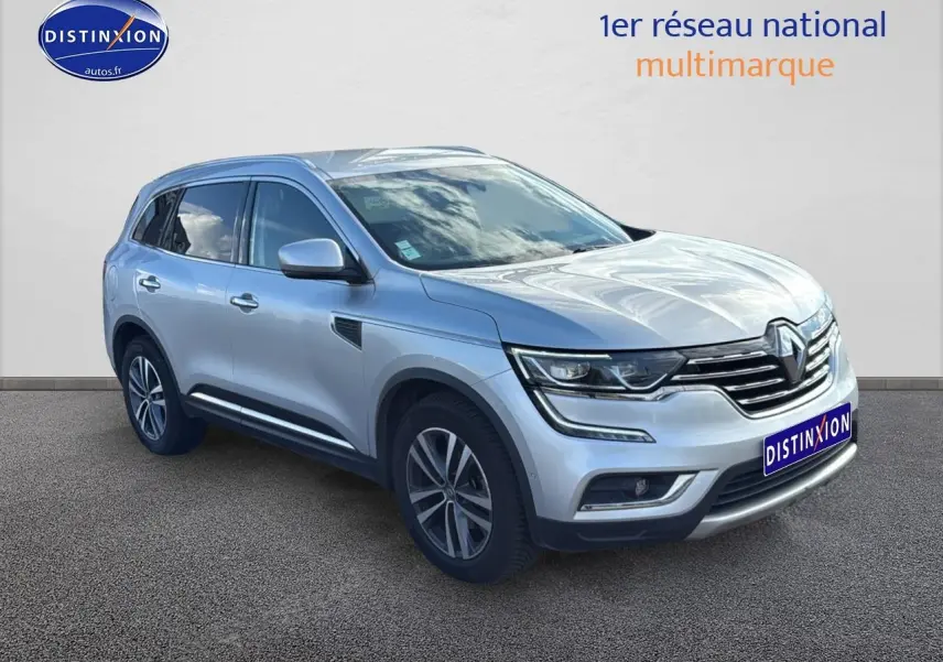 Renault Koleos gris en 3/4 avant droit avec jantes alu et calandre chromée sur fond neutre.