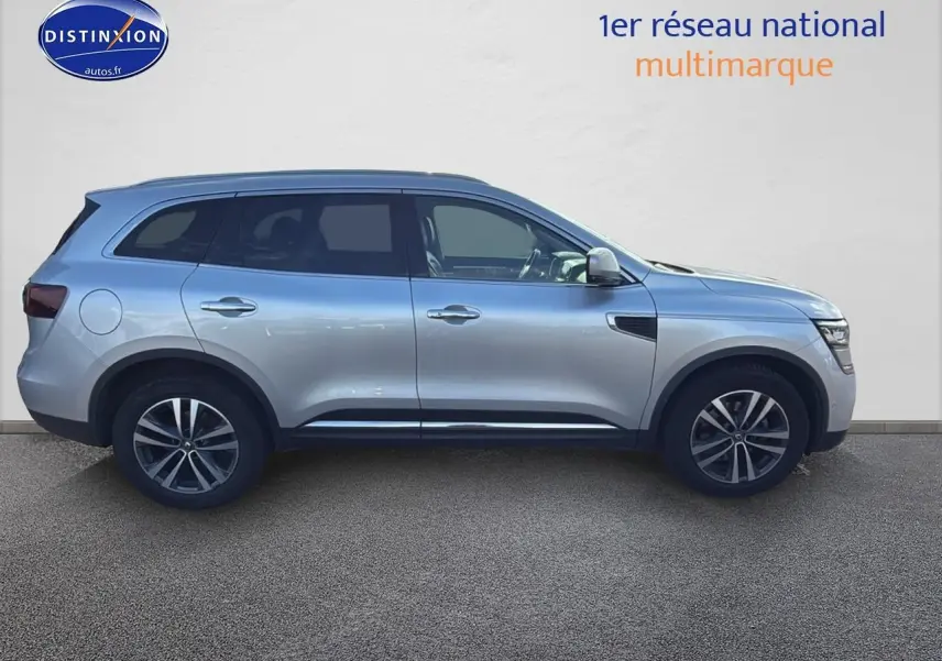 Profil côté gauche d'un Renault Koleos gris 2017 avec jantes alliage et barres de toit visibles.