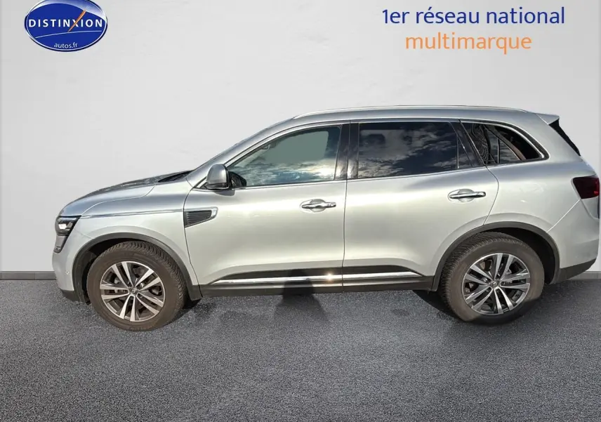 Profil côté gauche d'un Renault Koleos gris 2017 garé devant un mur blanc, avec jantes alliage visibles.