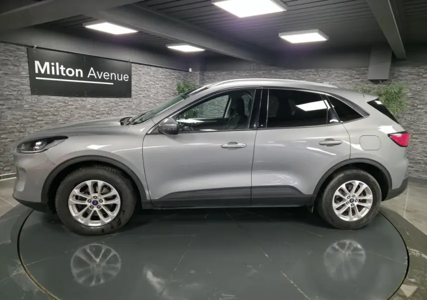 Profil côté gauche du Ford Kuga gris métallisé 2021 dans un showroom avec jantes alliage 17 pouces.