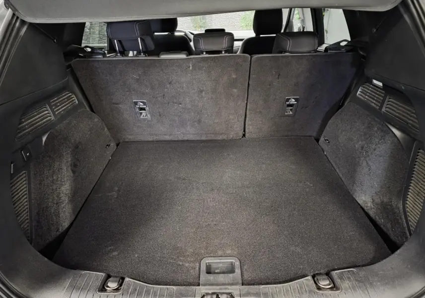Coffre spacieux du Ford Kuga 2021 vu de l'arrière avec banquette arrière en tissu et tapis de sol noir.