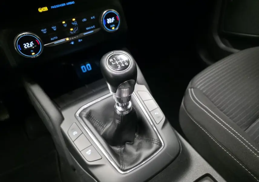 Levier de vitesses manuel noir en gros plan dans l'habitacle du Ford Kuga gris, avec console centrale et siège tissu visible.
