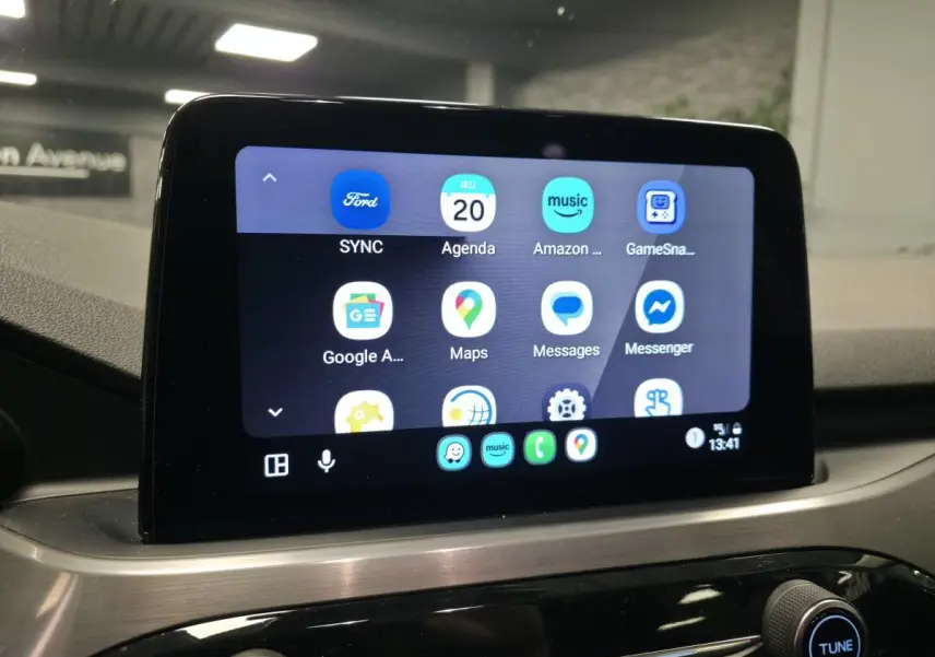 Écran tactile central du Ford Kuga 2021 affichant l'interface SYNC avec applications connectées, vue intérieure.