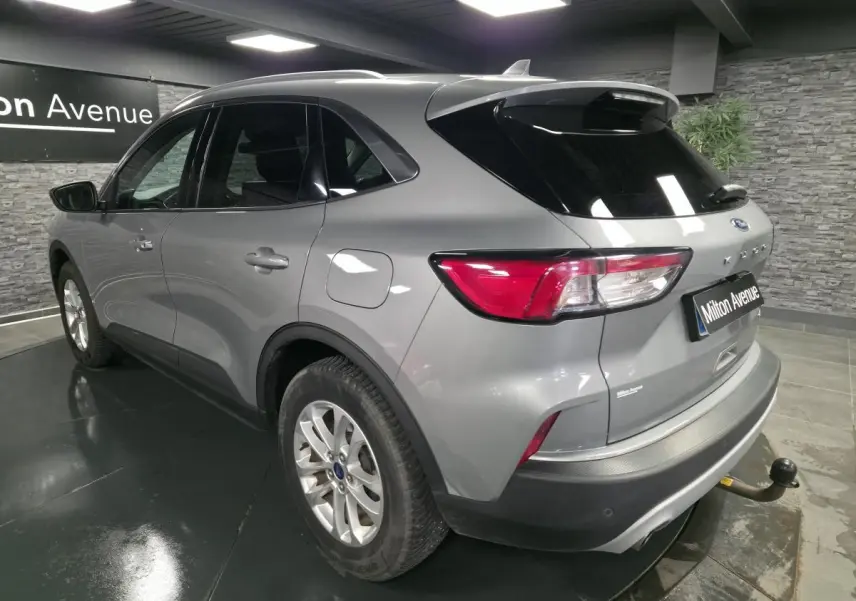 Vue 3/4 arrière droite du Ford Kuga gris métallisé avec crochet d'attelage et vitres arrière surteintées.