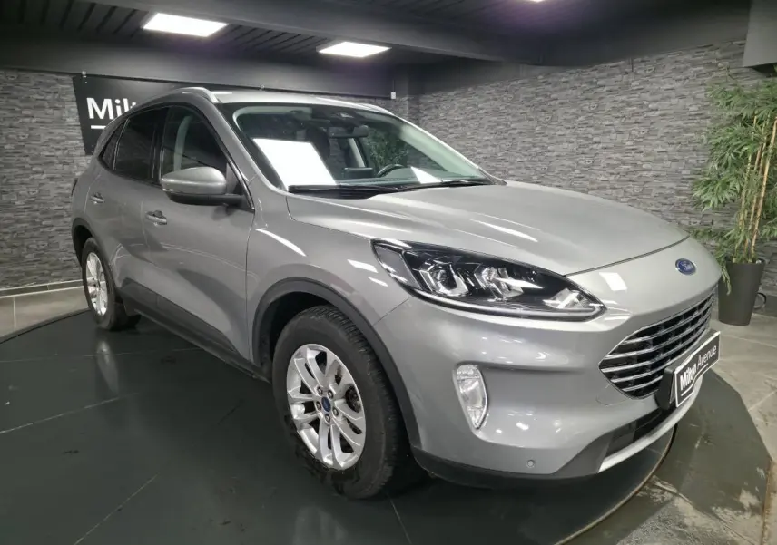 Vue 3/4 avant droite d'un Ford Kuga gris métallisé avec calandre Titanium et jantes alliage 17 pouces.