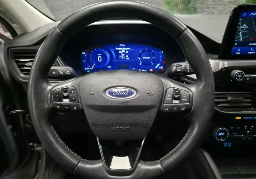 Vue rapprochée du volant noir en cuir du Ford Kuga 2021 avec tableau de bord numérique et écran tactile central.